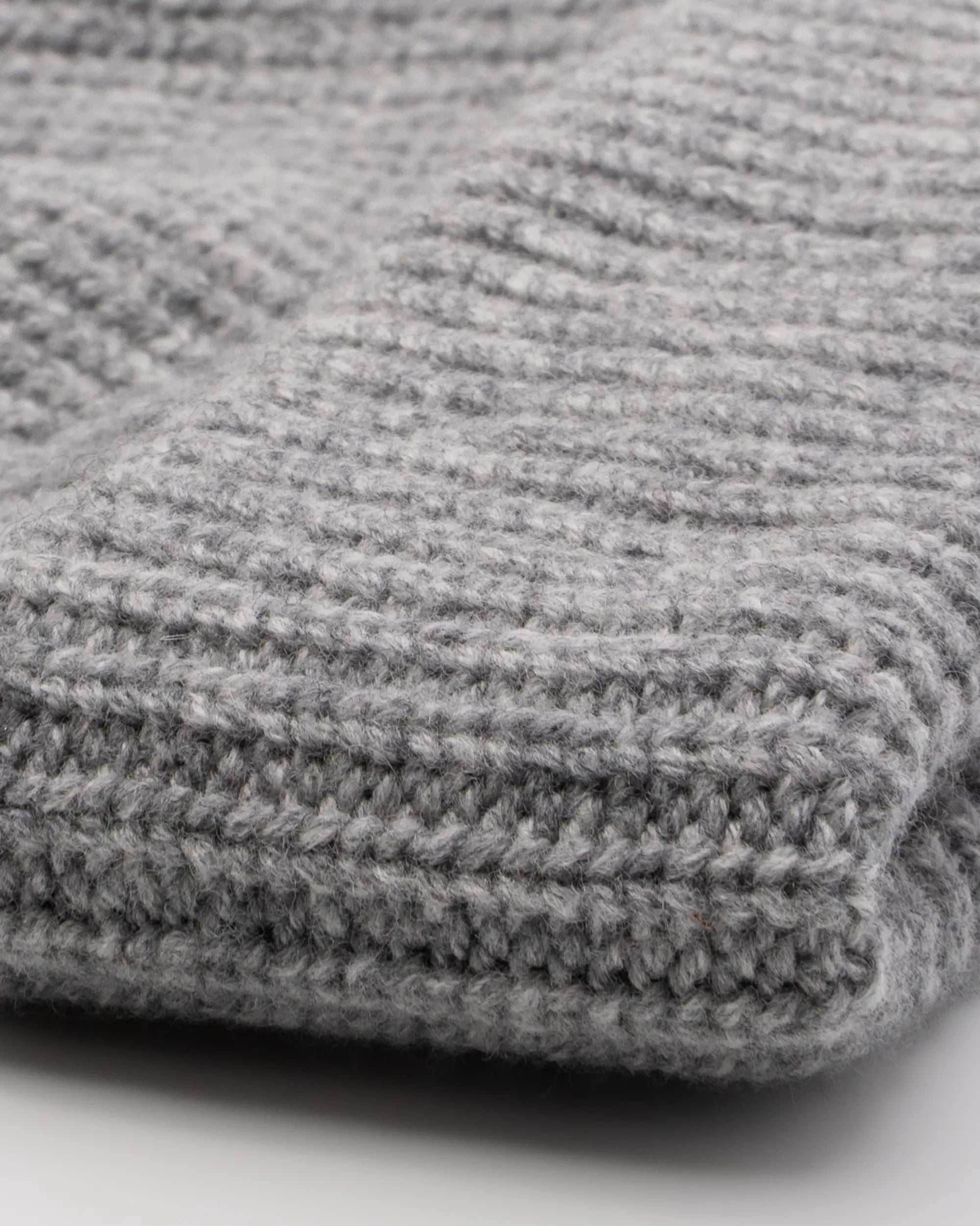 Close-up of gray knitted beanie with a ribbed texture.