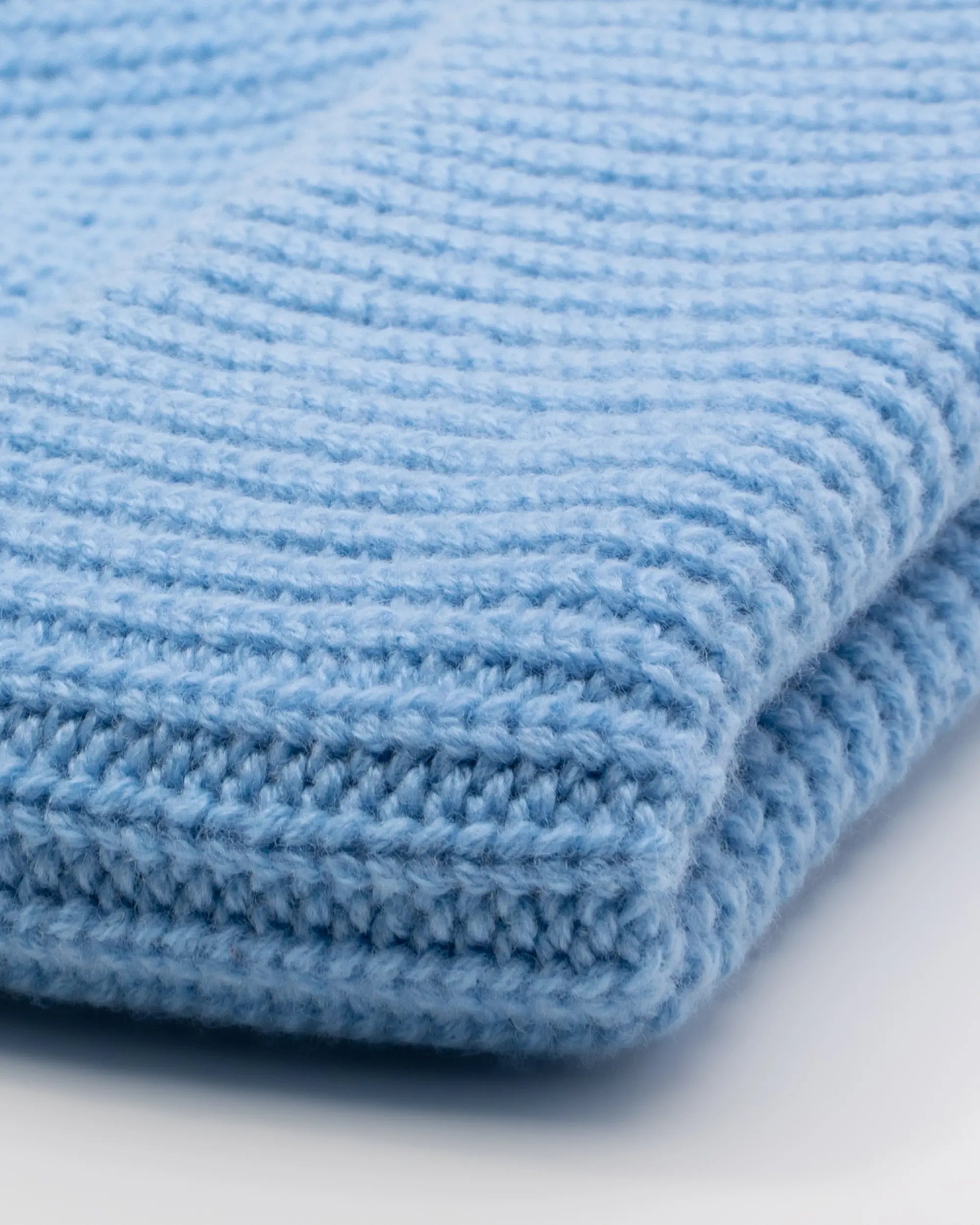 Close-up of a blue textured beanie on a light background