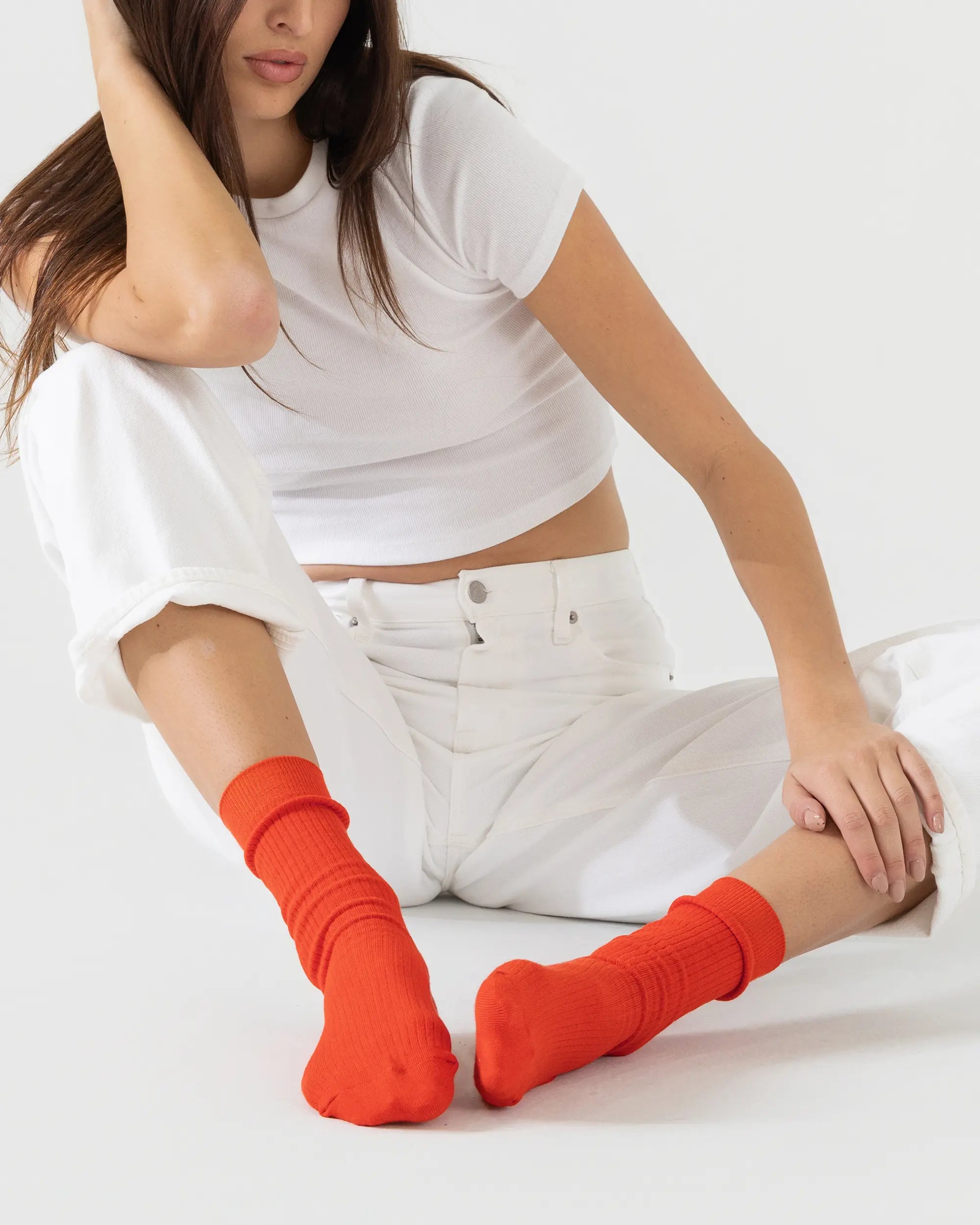 model wearing bright red socks in a white studio