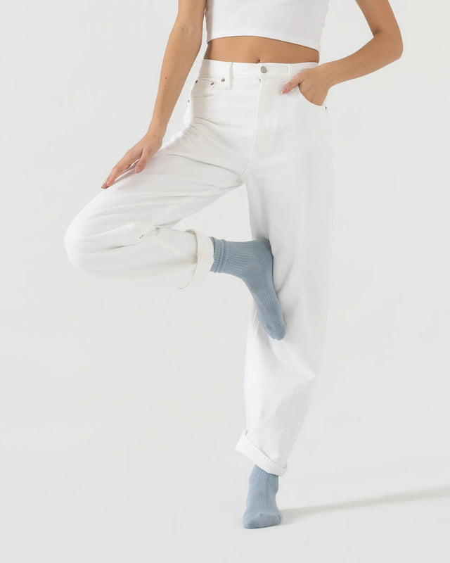 Person wearing light blue sporty socks with a white outfit on a plain background