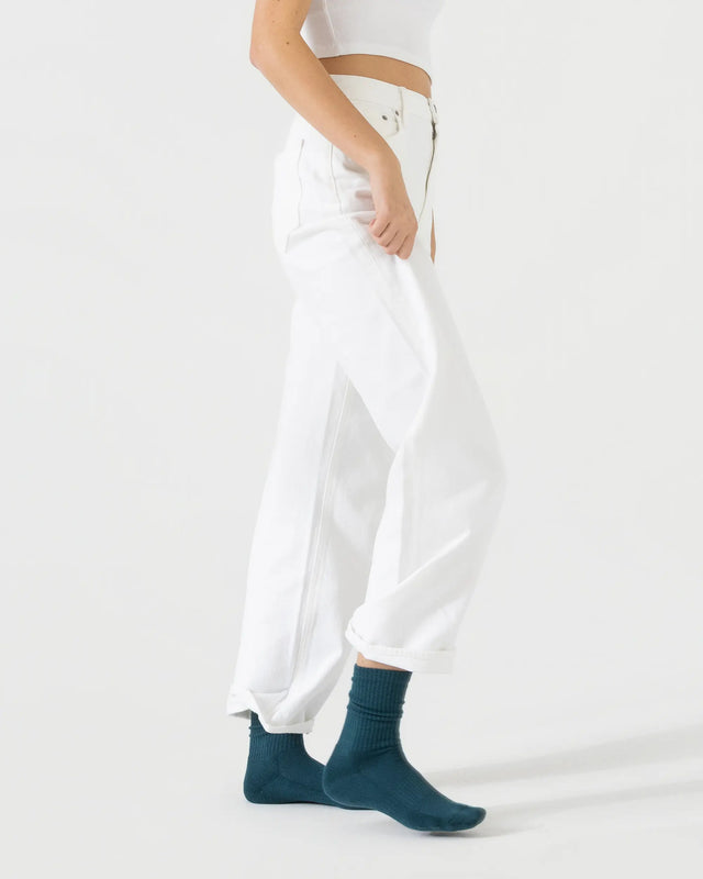 Person wearing dark green sporty socks with a white outfit on a plain background