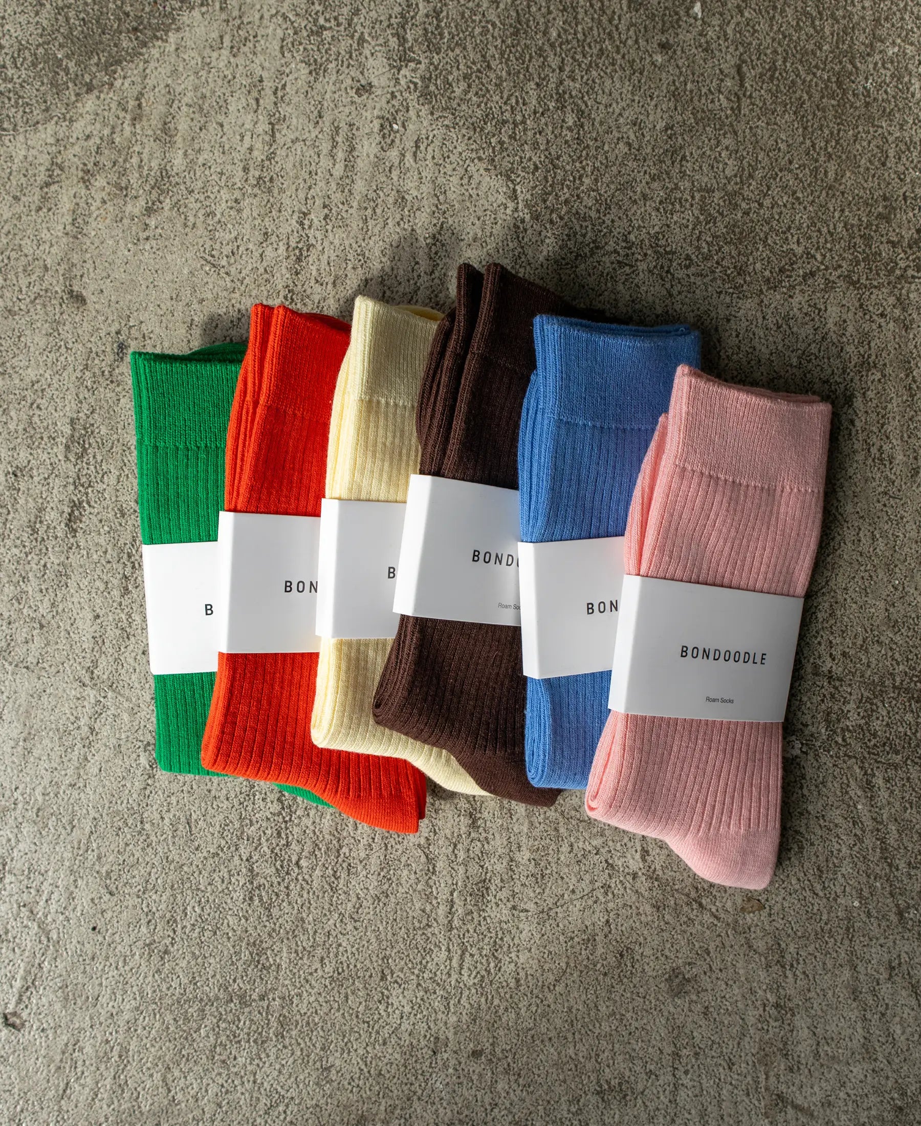 A selection of brightly colours cotton Roam Bondoodle socks on a concrete background