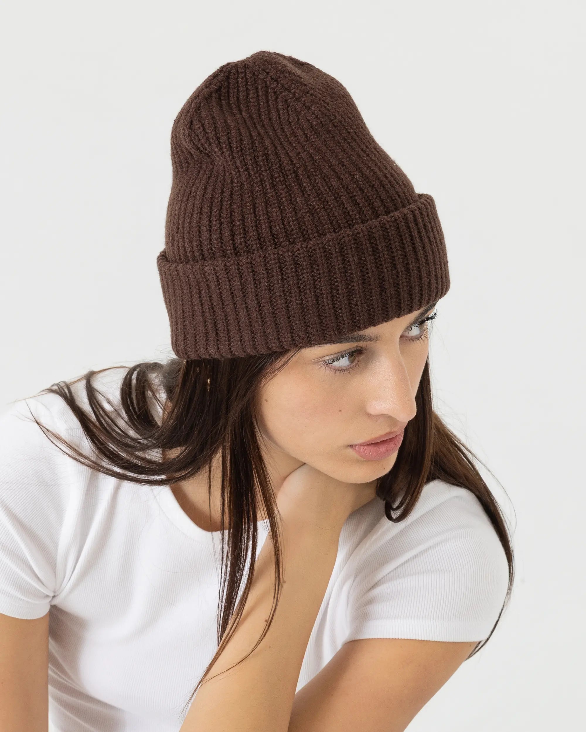 Woman wearing a brown knit beanie on a white background