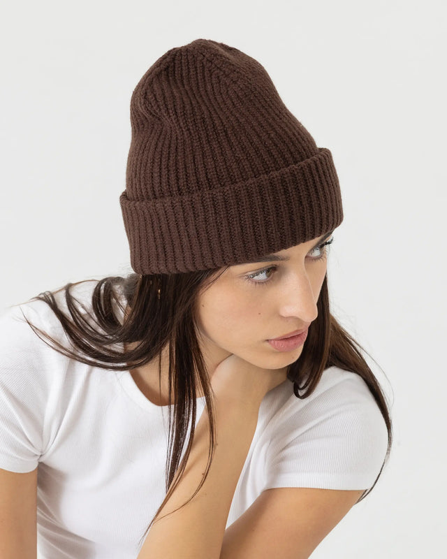 Woman wearing a brown knit beanie on a white background