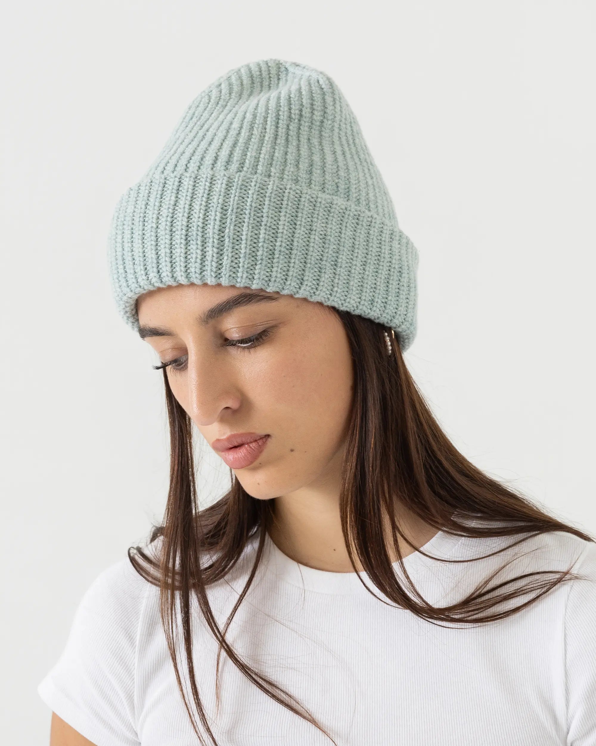 Woman wearing a light green knit beanie against a white background