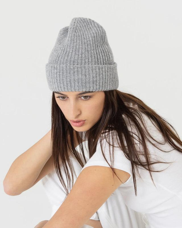 Woman wearing a gray knit beanie against a white background
