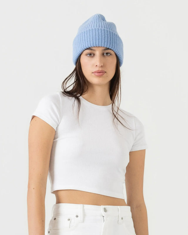 Person wearing a light blue beanie and white t-shirt on a plain background
