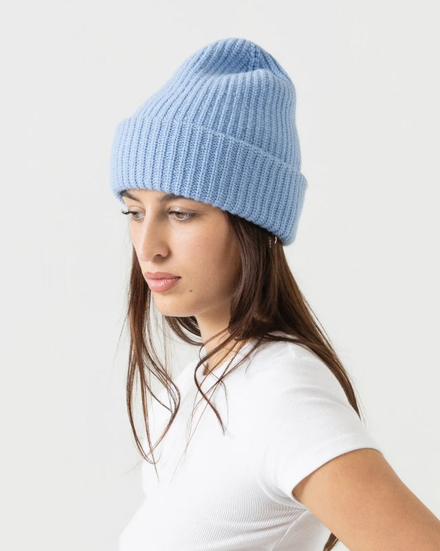 Woman wearing a light blue knit beanie on a white background
