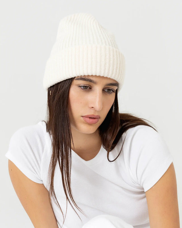 Person wearing cream merino wool beanie with a white outfit on a plain background