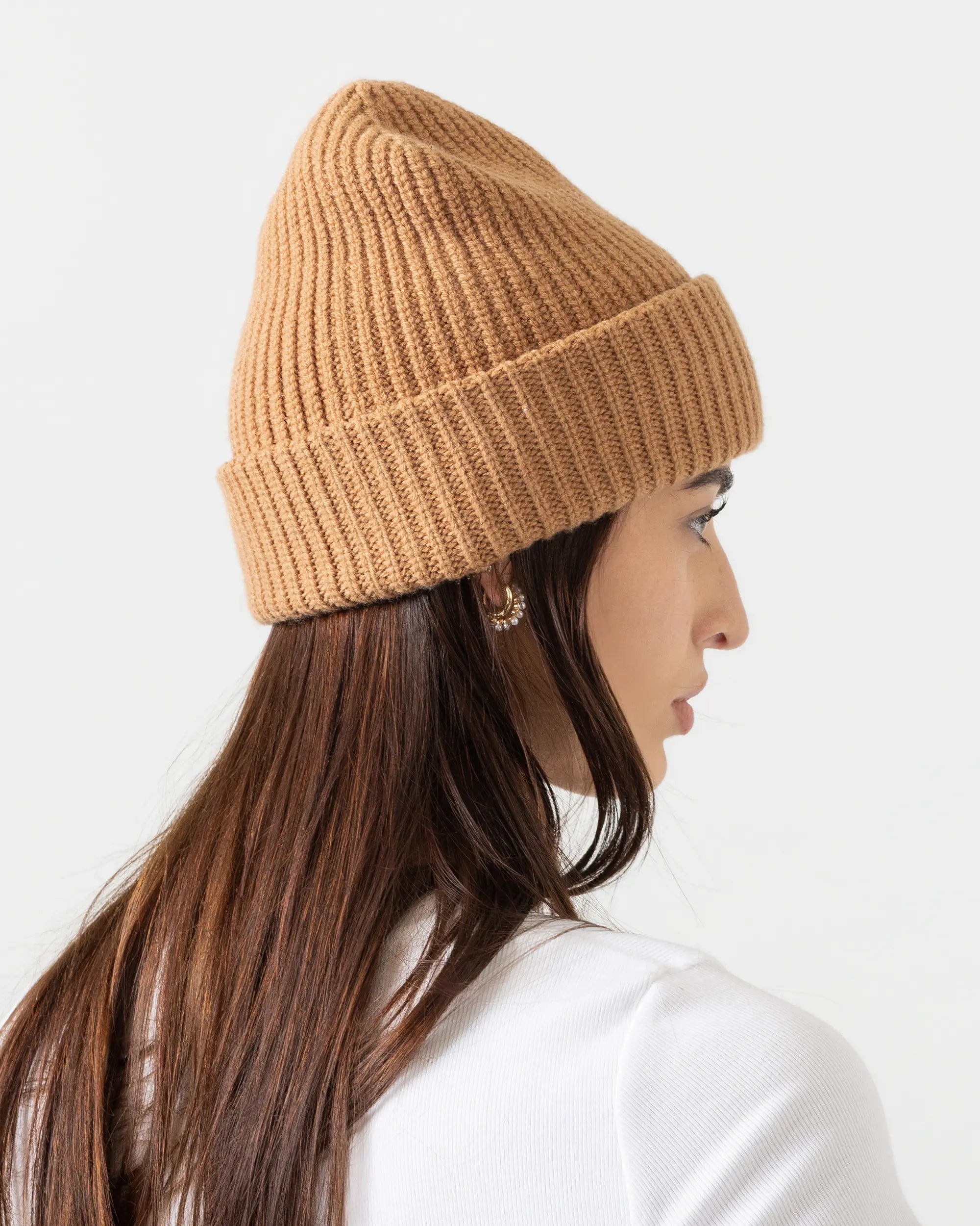 Woman wearing a brown knit beanie against a white background