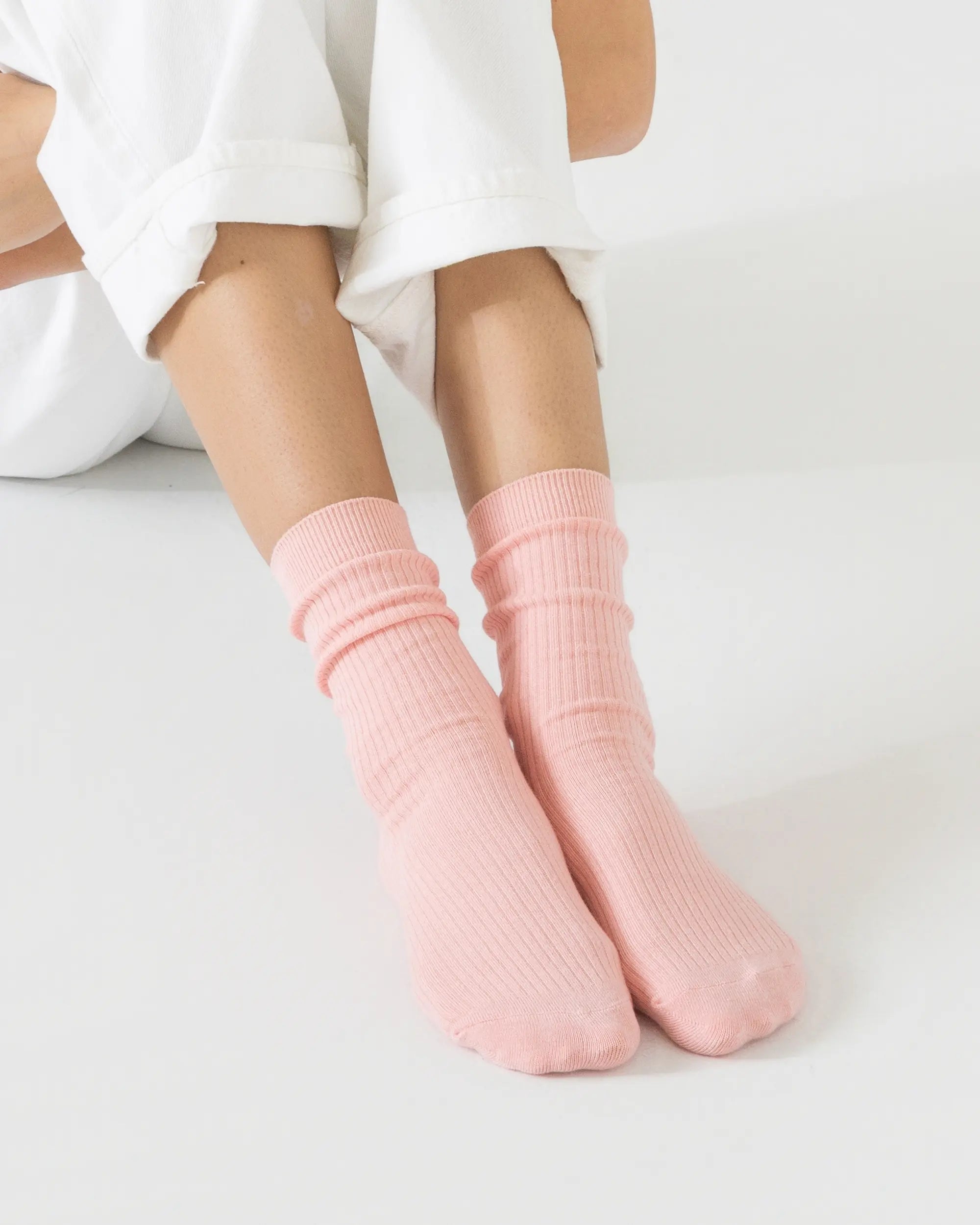 Person wearing light pink socks on a white background