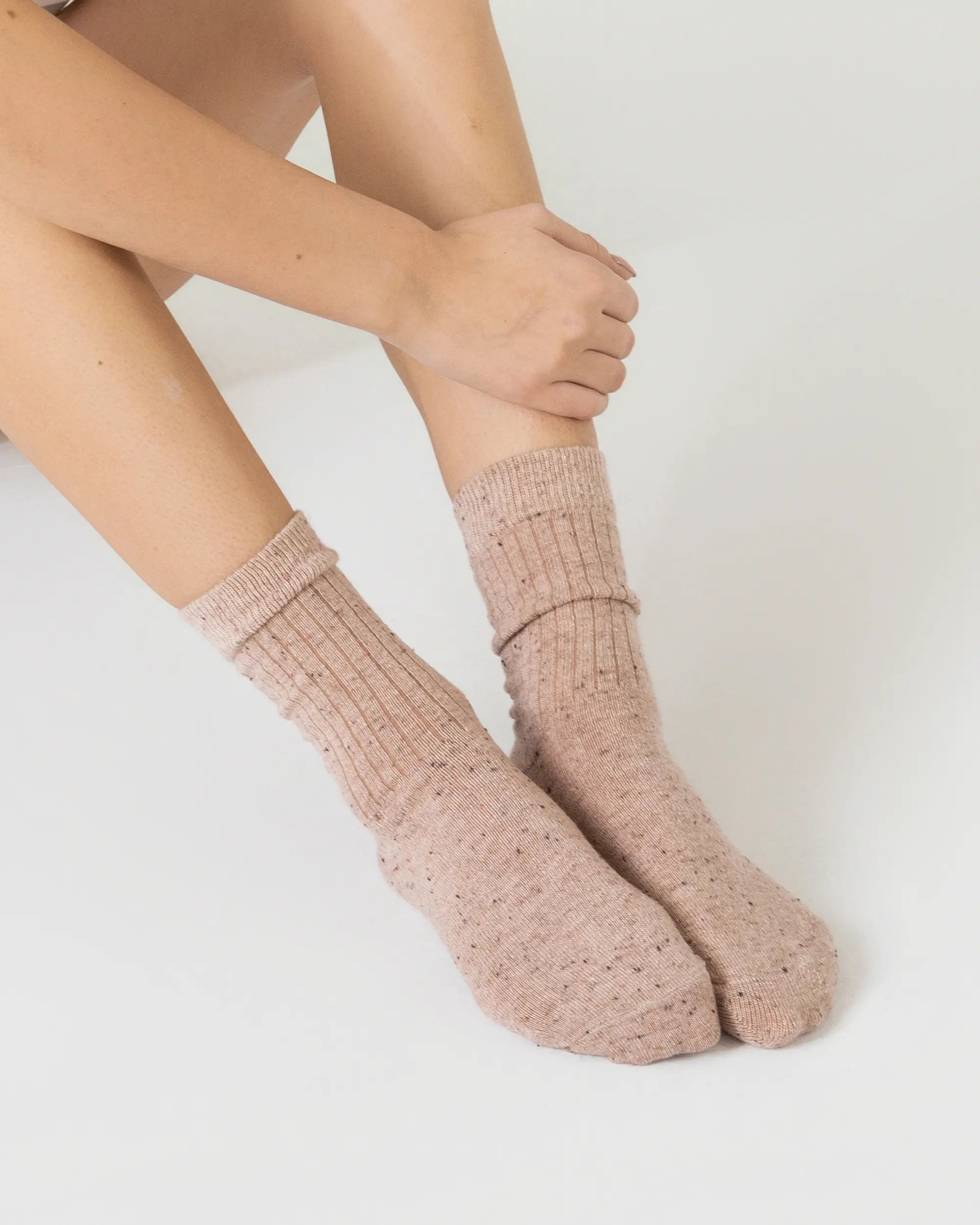 Person wearing pink textured socks on a light background