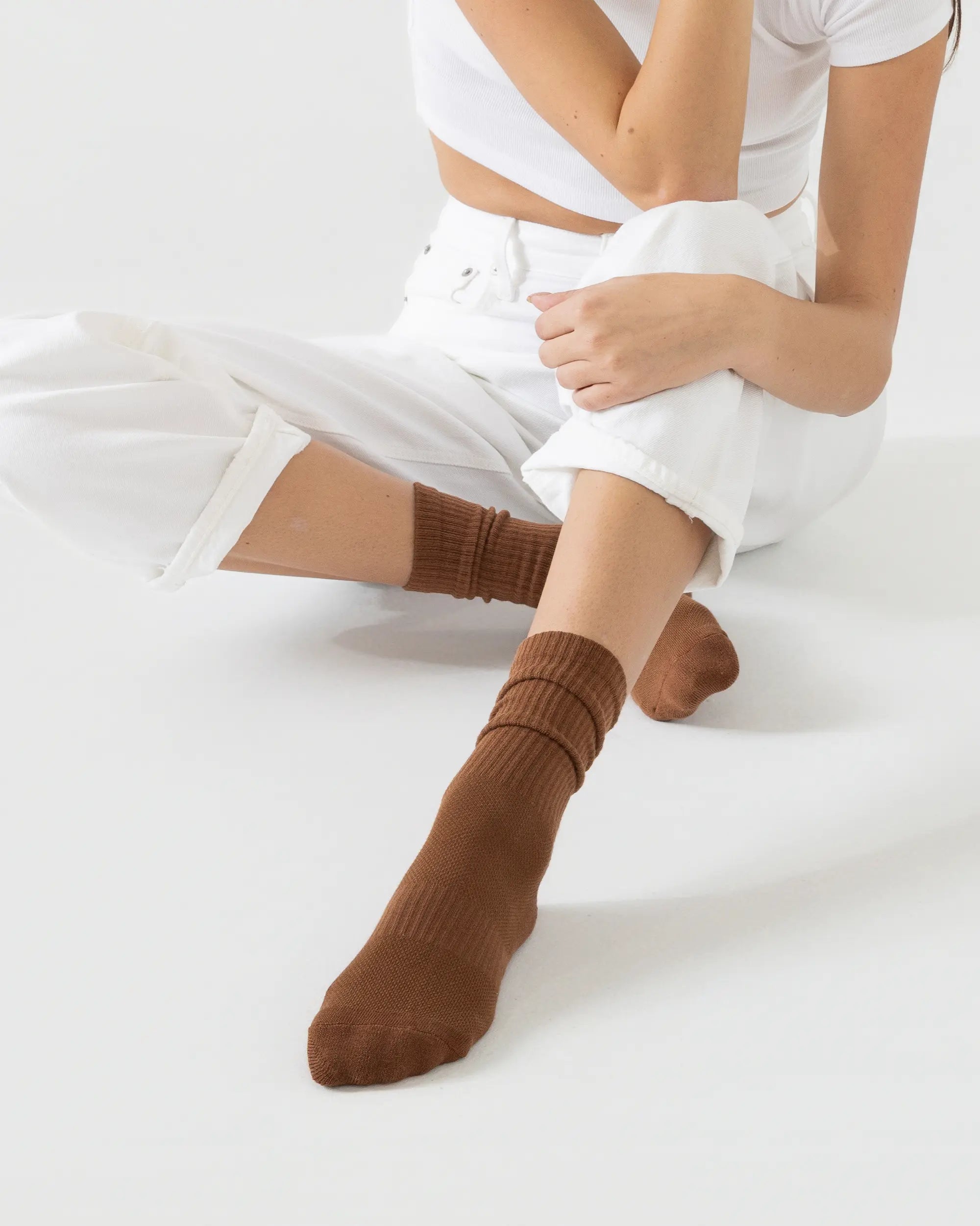 Person wearing brown socks and white pants on a light background