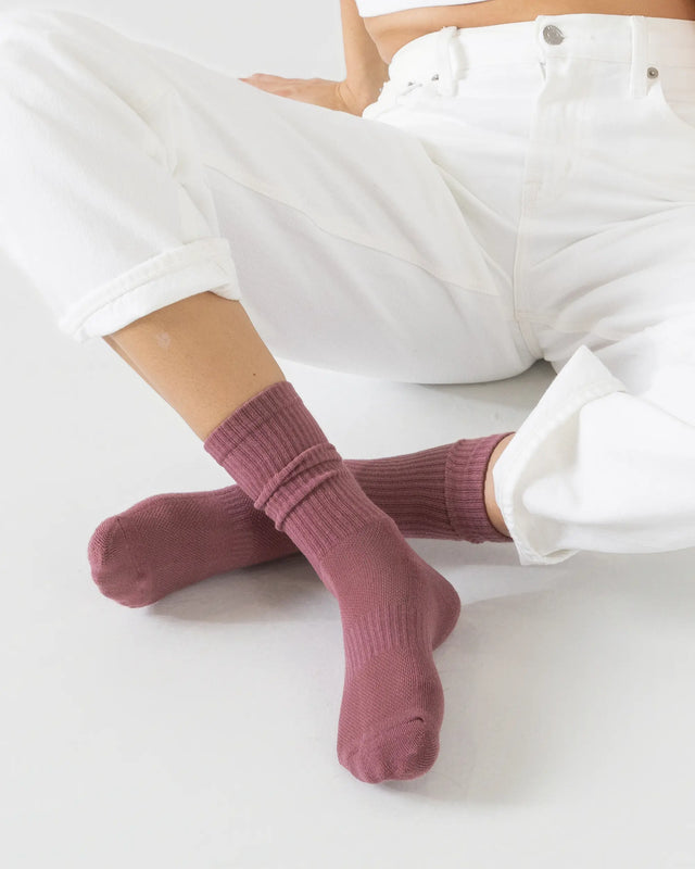 Person wearing dusty rose sport socks on a white background
