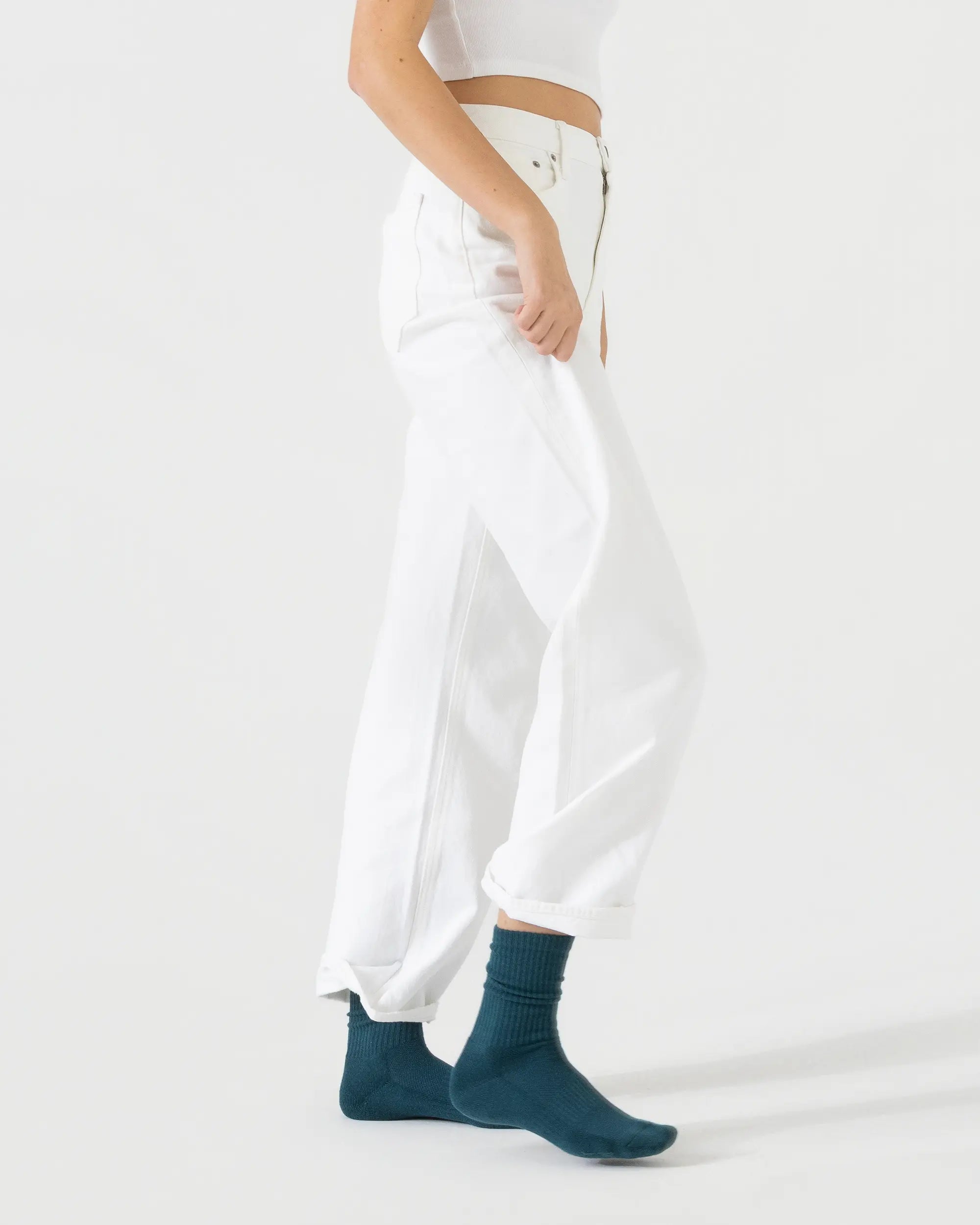 Person wearing dark green sporty socks with a white outfit on a plain background